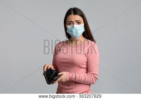 Coronacrisis Concept. Portrait Of Concerned Young Woman With Empty Wallet In Hands, Standing Over Li