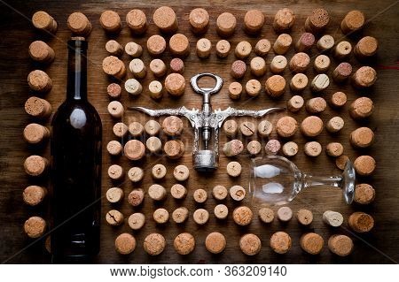 Wine Corks Of Different Sizes, A Corkscrew, A Bottle Of Wine And A Glass Shot On An Old Wooden Surfa