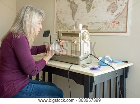 : DAYTON, OHIO - APRIL 24, 2020:Woman sews homemade face masks from Hepa sweeper bags for use during COVID-19 pandemic as N95 masks are being reserved for medical personnel. Hepa filters filter 99.97.