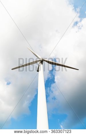 Wind Turbine Against A Cloudy Blue Sky