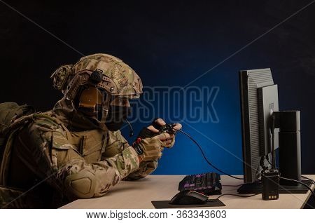 A Guy In A Military Uniform Is Sitting Playing Computer Games On A Computer With A Joystick