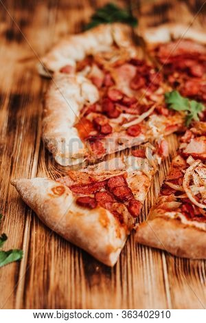 Clice Of Pizza With Pepperoni And Salami On A Rustic Wooden Background