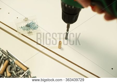 An Electric Screw With A Cruciform Bat Wraps A Self-driving Screw Into The Furniture Cabinet, Screws