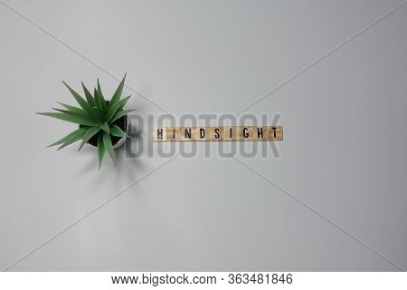 The Word Hindsight Written In Wooden Letter Tiles On A White Background.
