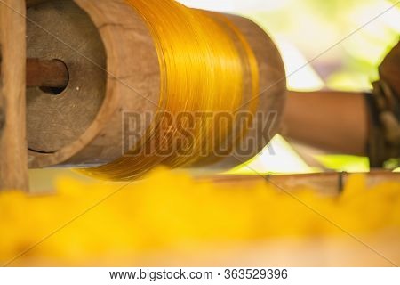 Wheel Spinning Yarn With Yellow Thread To Work For Weaving Machine And Thai Traditional Silk.