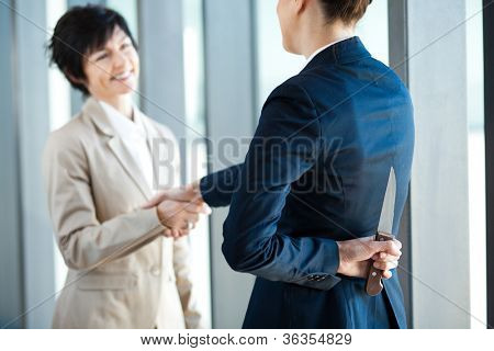 nebezpečné podnikatelka drží nůž za jejími zády, zatímco handshake