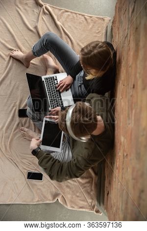 Attractive Young Couple Using Devices Together, Tablet, Laptop, Smartphone, Headphones Wireless. Com