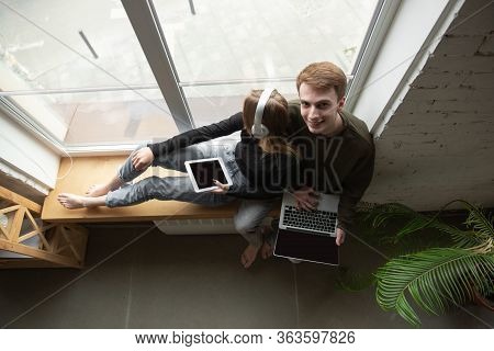 Attractive Young Couple Using Devices Together, Tablet, Laptop, Smartphone, Headphones Wireless. Com
