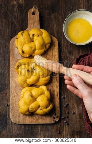 Female Hands Making Egg Wash On Brioche With Chocolate Chips