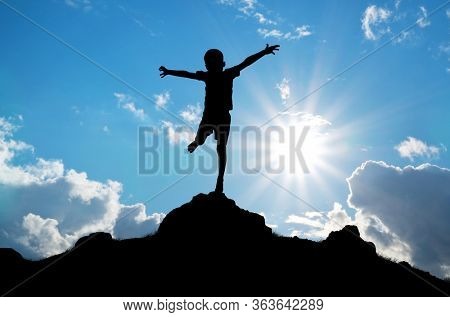 Happy silhouette of boy enjoy the nature. Spread arms to the sun and deep sky. Emotional and coceptual scene.