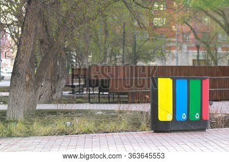 Four Waste Sorting Baskets On The City Street For Paper, Plastic, Glass And Unsorted Garbage