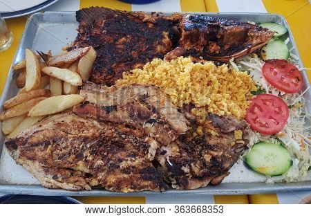Grilled Fish Fillets Served With Yellow Rice, Salad And Potatoes, Restaurant