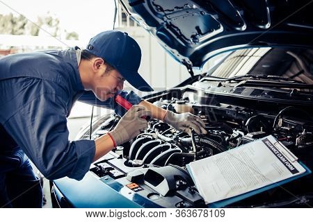 Car Mechanic Technician Holding Flashlight Checking Engine With Checklist Clipboard To Maintenance V