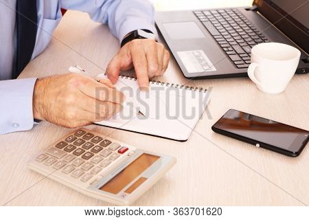 A Businessman Holds A Pen And On Schedule Calculate Data. The Graph Chart Shows The Effectiveness Of