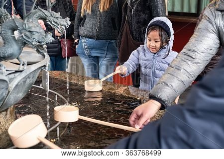 Japan, Tokyo Hot Spot, Kid Scooping Water By Wooden Dipper At Temizuya, Chozuya Before Entering Shri