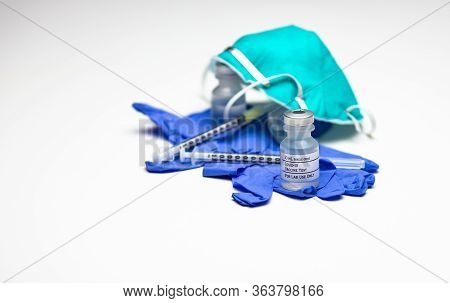 Two Syringes On Top Of Blue Medical Gloves With Two Vials Of Covid-19 Test Vaccine And A Respirator 