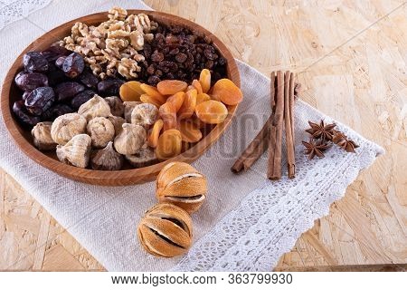 Zimt, Dried Apricot, Nuts, Faygi, Dates In A Wooden Cup On A Tablecloth On A Wooden Background
