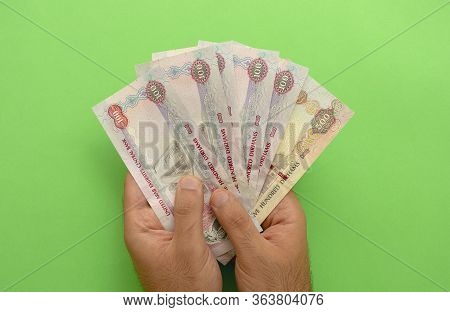 Uae National Currency. Uae Money Banknotes. Young Man Holds In His Hands Dirhams On Green Background