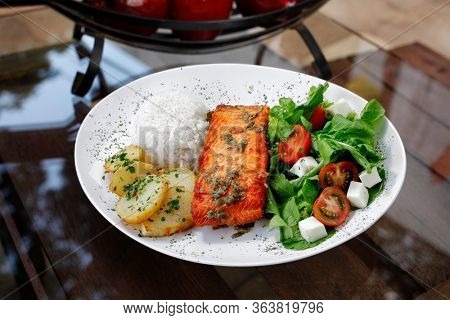 Grilled salmon with potatoes, arros, lettuce and tomatoes