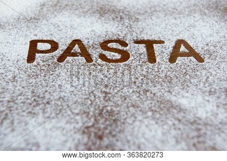 Wooden Background With Sprinkled Flour And The Word Pasta Written. Seletive Focus