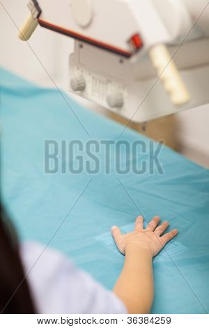 Donna ponendo la sua mano su una tabella medica in una stanza di radiografia