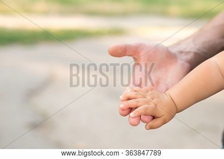 A Parent Father Holds The Hand Of A Small Child, Copy Space