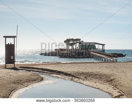 Two Guys Sit In Lifeguard Tower And Watch Amazing Panorama Of Bay With Island Restaurat. Summer Holi