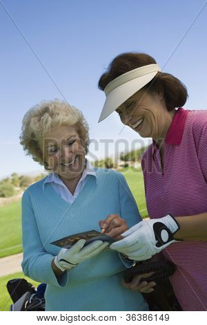 Due amici femminili scrivendo i loro punteggi golf su scheda