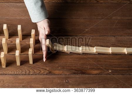 Businesswoman Protecting Dominoes From Falling On Wooden Desk. Business Assistance And Leadership In