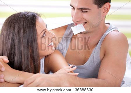 Jovem casal atraente na cama com um preservativo