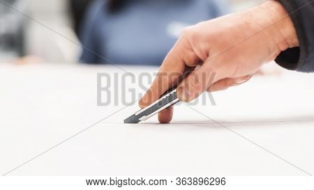 Close-up Of Hand With Skalpel. Worker Cut Paper In Printshop
