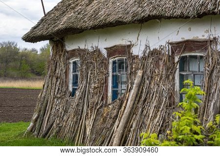 Old Vintage Rural House In Ukrainian Countryside Style. House With A Cattail Roof. The Roof Of The R