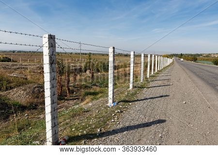 State Border Between Kyrgyzstan And Uzbekistan, Road Along A Barbed Wire Fence.