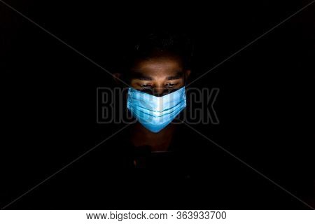 Bangladesh – April 14, 2020: A Blue Surgical Mask-wearing Young Man Was Playing Mobile Games At Dhak