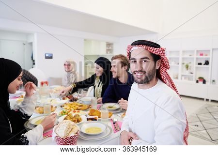 young arabian man having Iftar dinner with muslim family Eating traditional food during Ramadan feasting month at home. The Islamic Halal Eating and Drinking Islamic family