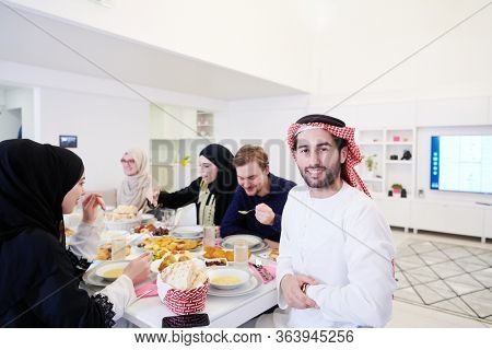 young arabian man having Iftar dinner with muslim family Eating traditional food during Ramadan feasting month at home. The Islamic Halal Eating and Drinking Islamic family