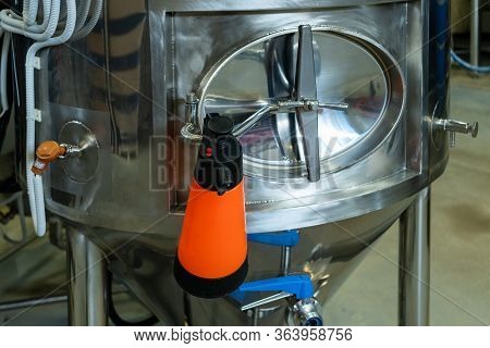 Cleaning The Inside Of The Brewery. Mop For Water On The Background Of Beer Tanks.