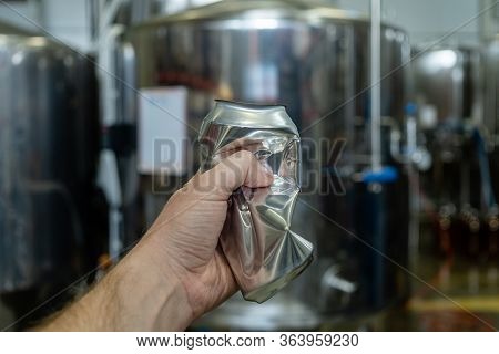 Male Hand Wrinkles An Empty Aluminum Can On The Background Of Beer Equipment