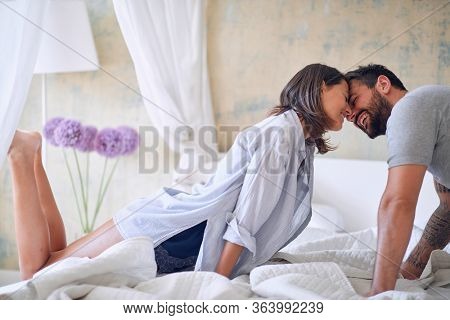 Man kissing woman.
Attractive couple in love in bed sheets.