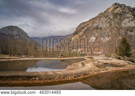 Mountains And Trees Reflecting In Artificial Ponds. Surba Town Hiding Behind Trees At The Foothill O