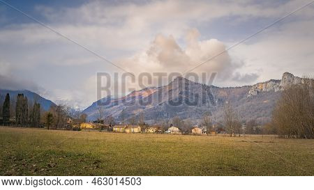 Surba Town Hiding Behind Trees At The Foothill Of Pyrenees Mountains With Snowy Peaks In Background,