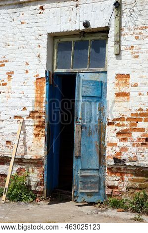 Weathered Timeworn Shabby Wooden Door Entrance To Old Brick Building.
