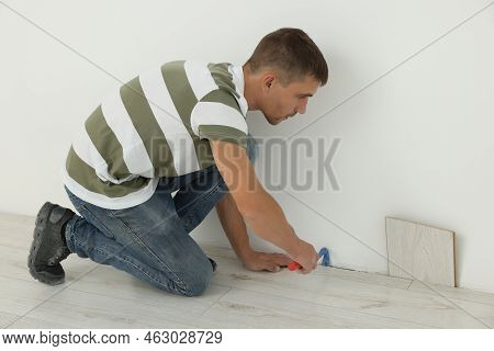 Professional Worker Using Nail Puller During Installation Of New Laminate Flooring Indoors