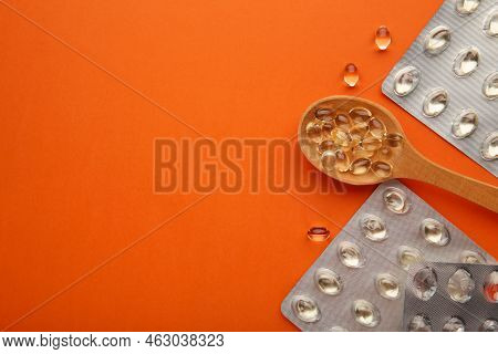 Vitamin D Yellow Pills On Wood Spoon On Orange Background. Medicine Tablets Of Vitamin D On Table. T