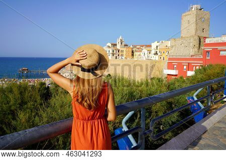 Beautiful Girl Holding Hat Looking At Termoli Landscape With Historic Town And Beach In Molise, Ital