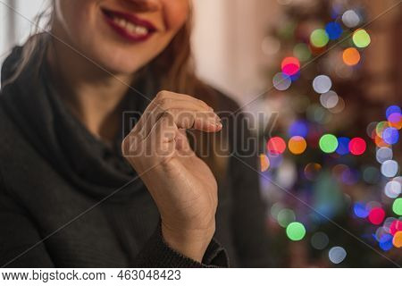 Cropped View Smiling Girl Making A Half Of Heart Symbol With Her Hands. Blurred Christmas Tree On Ba