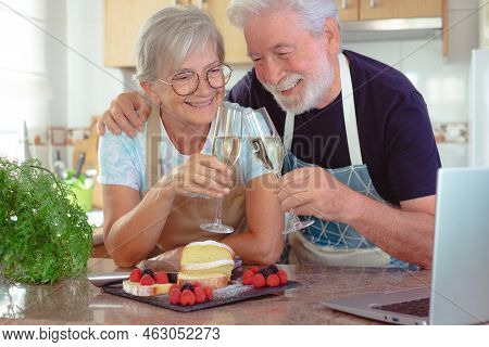 Beautiful Senior Couple In The Home Kitchen Looking At Their Homemade Plumcake Ready To Eat, Toastin