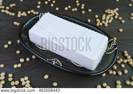A Plate Of Fresh Tofu Bean Curd On With Dried Soybeans Scattered On Wooden Table
