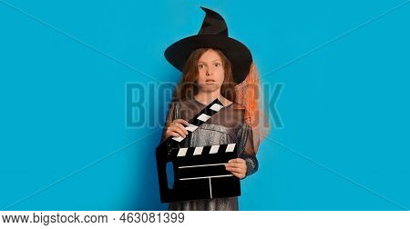 Scared Little Girl In Witch Costume Holding Classic Film Making Clapperboard And Looking At Camera O