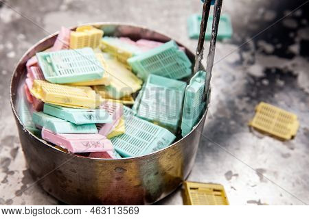 Cassettes With Biopsy Samples In Hot Paraffin. Scientist Embedding Tissues In Paraffin Blocks For Se